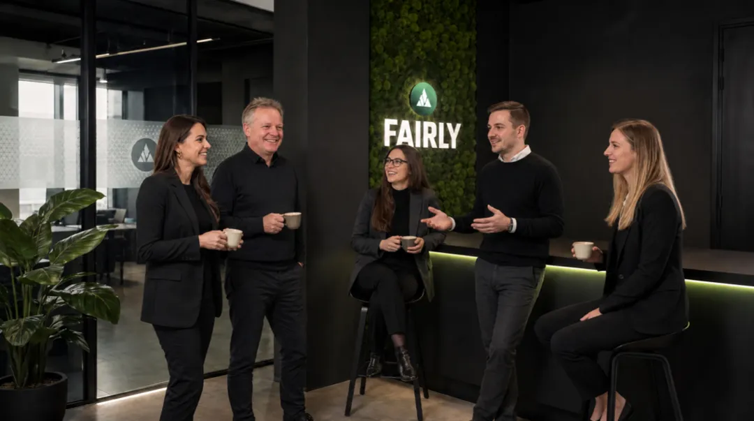 Das Fairly-Team im Gespräch an der Logowand im Büro